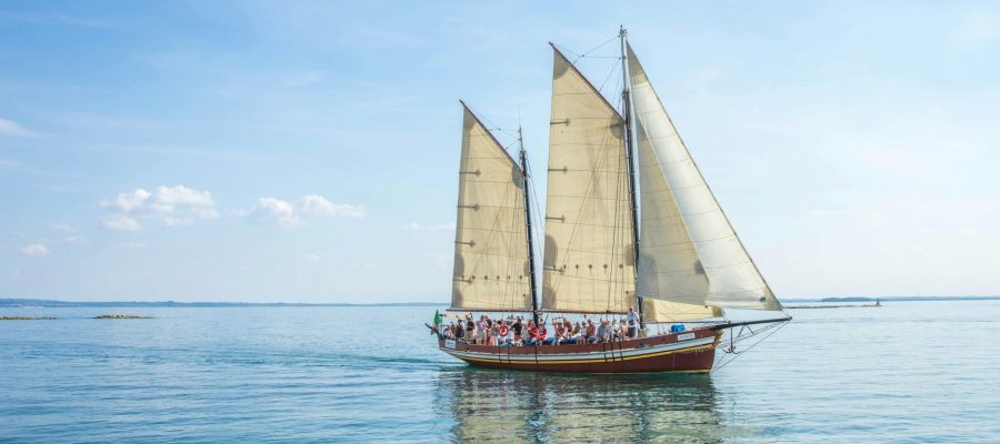 A picturesque sailboat with people enjoying a day at sea under clear skies.